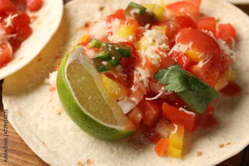 Delicious taco with vegetables, lime and ketchup on wooden table, closeup