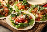Delicious tacos with vegetables and meat on table, closeup