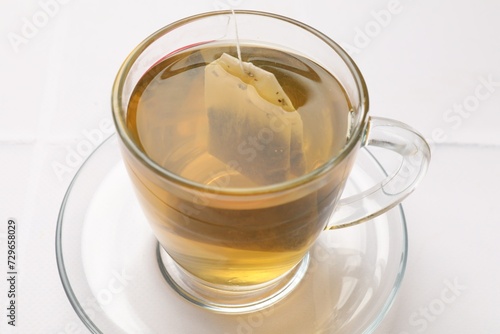 Tea bag in cup with hot drink on white table, closeup