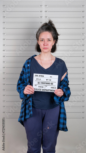 Brunette caucasian woman standing with criminal mugshot letter board at police department photo