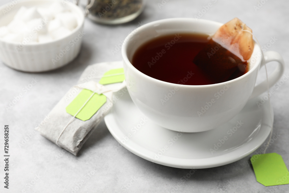 Tea bags and cup of hot beverage on light table, closeup Tea bags and cup of hot beverage on light table, closeup