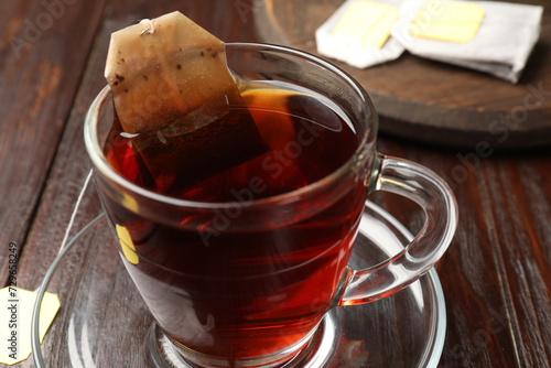 Brewing tea. Glass cup with tea bag on wooden table, closeup