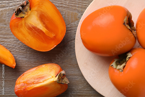 Whole and cut delicious ripe persimmons on wooden table, flat lay