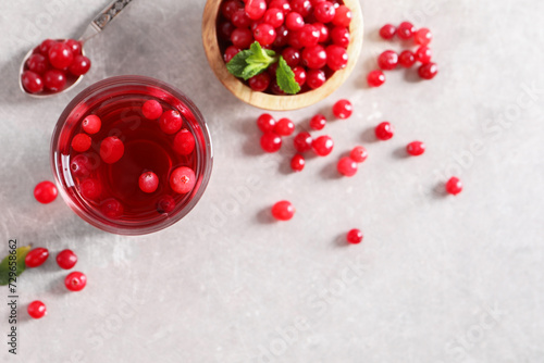 Tasty cranberry juice in glass and fresh berries on light grey table, top view. Space for text