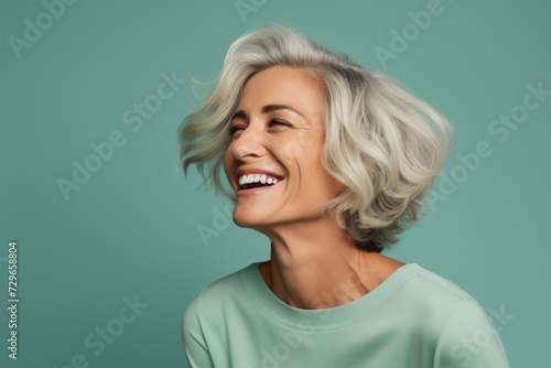 Cheerful mature woman laughing and looking away while standing against blue background