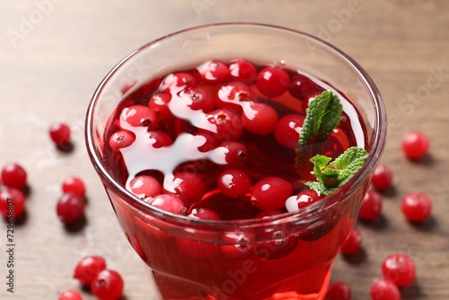 Tasty cranberry juice in glass and fresh berries on wooden table, closeup