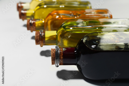 Vegetable fats. Different cooking oils in glass bottles on white background, closeup. Space for text