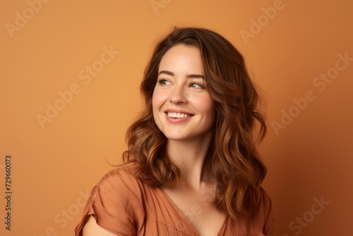 Portrait of a smiling young woman with long wavy hair on brown background