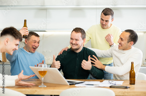 Group of football fans drinking beer and watching football match on a laptop at home