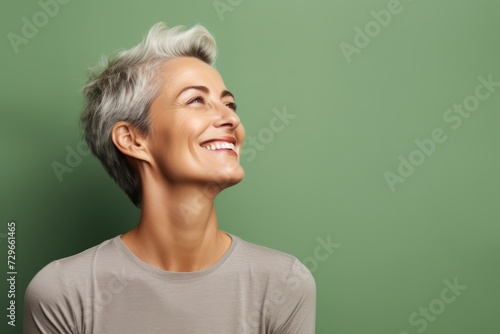 Portrait of smiling senior woman looking up at copy space on green background