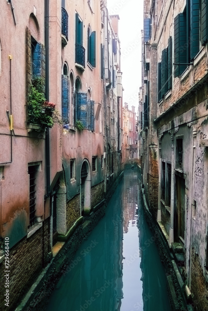 Small waterways of Venice. River canal with old colorful buildings in foggy day, Italy. Typical boat transportation. Venetian travel urban scene. Water transport. Popular tourist destination.