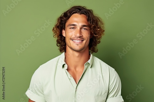 Portrait of a handsome young man smiling at camera against green background