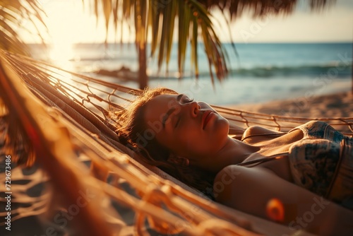 A woman peacefully rests in a hammock, swaying gently to the rhythm of the ocean waves. photo