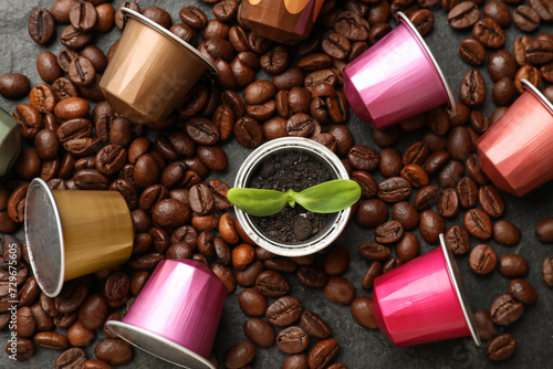 Coffee capsules with seedling and beans on black table, flat lay photo
