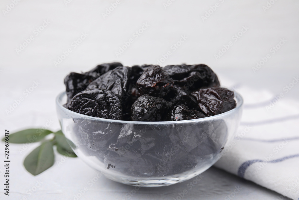 Sweet dried prunes in bowl on light table, closeup Sweet dried prunes in bowl on light table, closeup