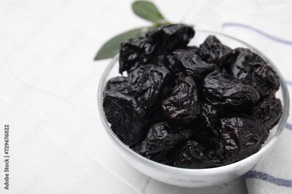 Sweet dried prunes in bowl on white table, closeup. Space for text Sweet dried prunes in bowl on white table, closeup. Space for text