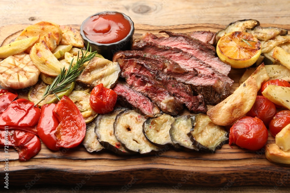 Delicious grilled beef with vegetables, tomato sauce and spices on table, closeup