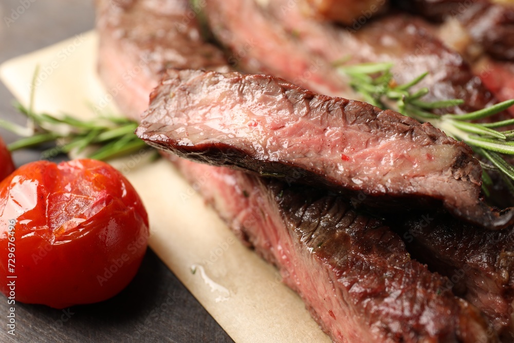Delicious grilled beef with rosemary and tomato on table, closeup