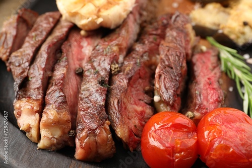 Delicious grilled beef with tomatoes and spices on tray, closeup