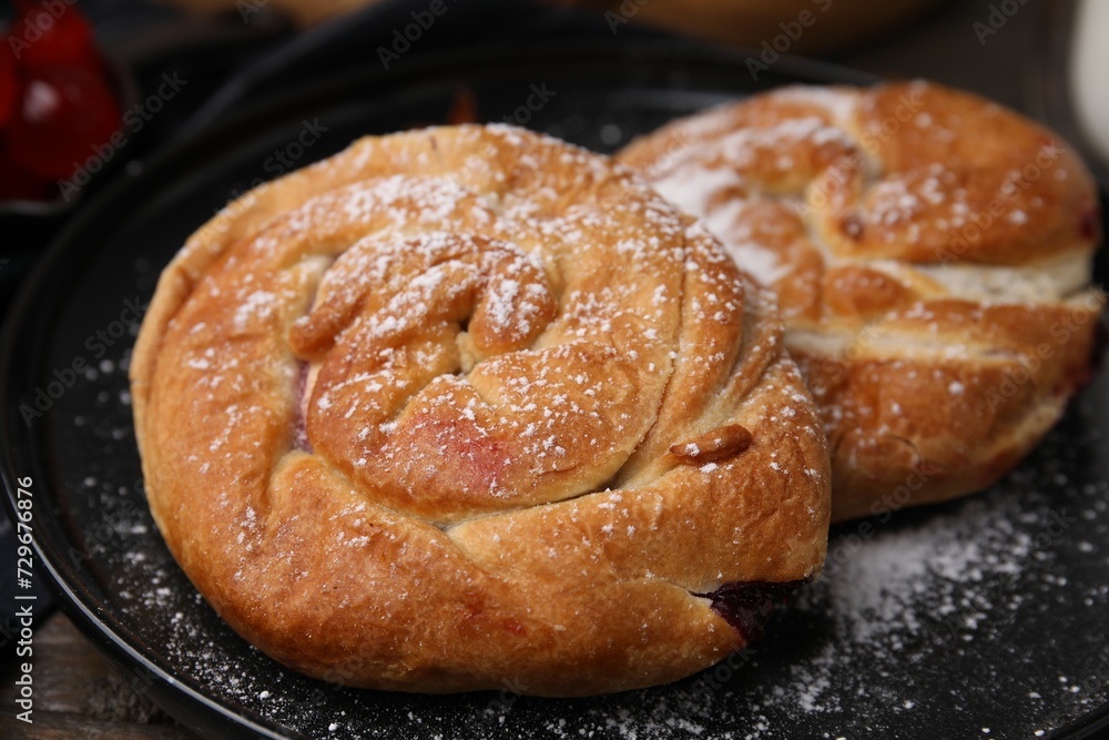 Delicious rolls with sugar powder on table, closeup. Sweet buns