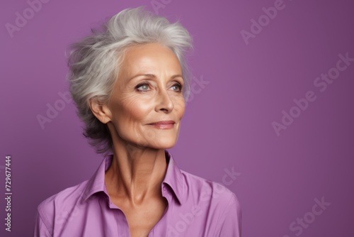 Portrait of beautiful senior woman with grey hair on purple background.