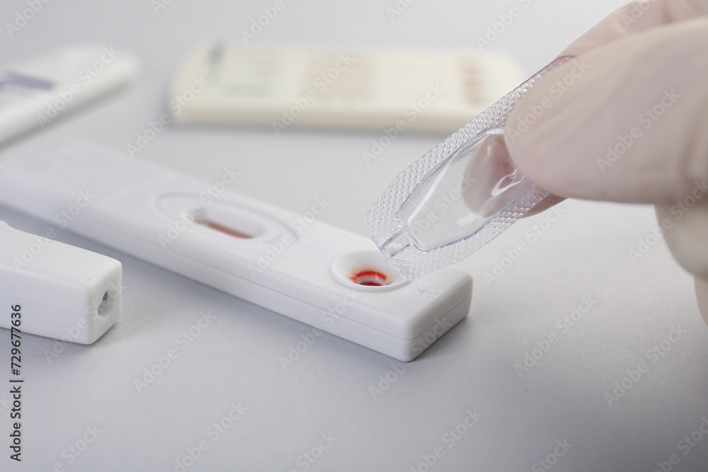 Doctor dropping buffer solution onto disposable express test cassette on light background, closeup Doctor dropping buffer solution onto disposable express test cassette on light background, closeup