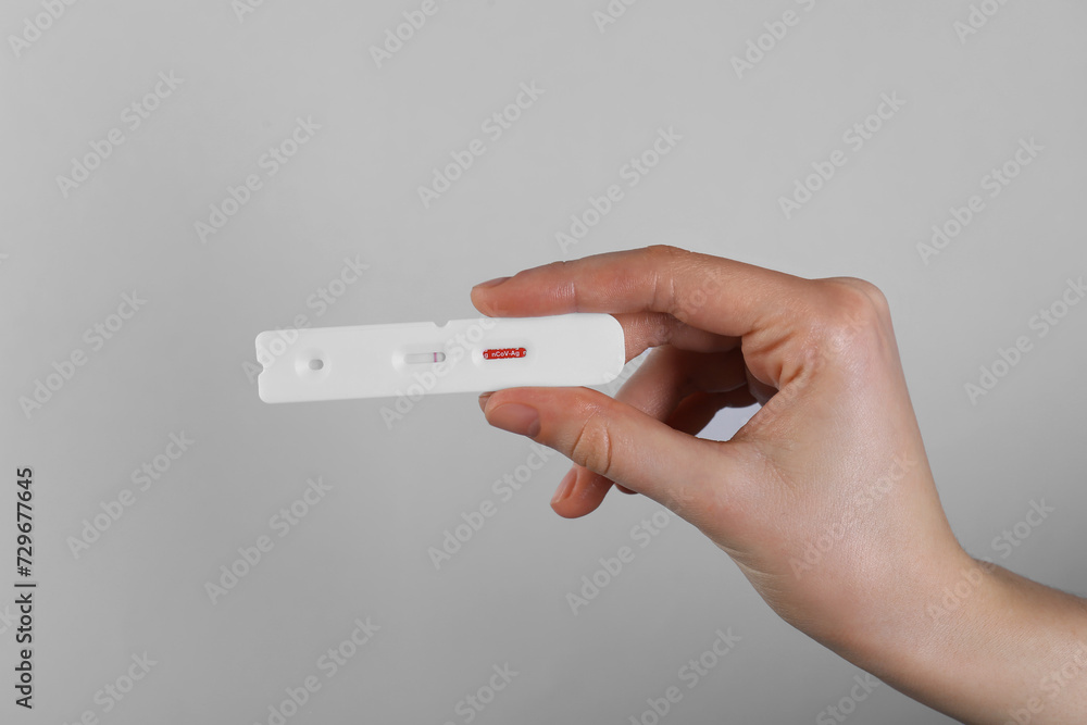 Woman holding disposable Covid-19 express test on light grey background, closeup Woman holding disposable Covid-19 express test on light grey background, closeup