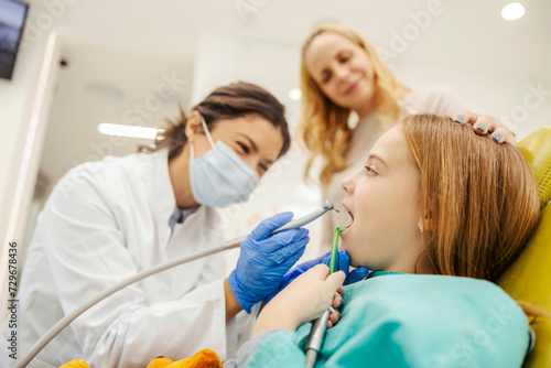 A brave girl during tooth drilling procedure at dentist office.