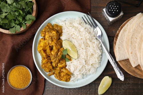 Delicious chicken curry with rice and ingredients on wooden table, flat lay
