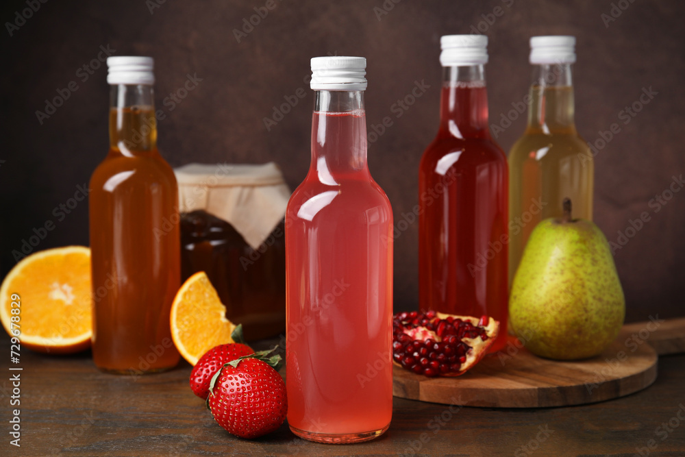 Delicious kombucha in glass bottles, jar and fresh fruits on wooden table Delicious kombucha in glass bottles, jar and fresh fruits on wooden table