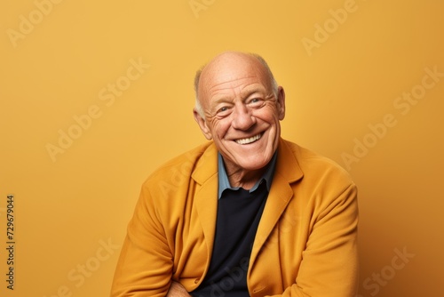 Portrait of smiling senior man looking at camera isolated on yellow background