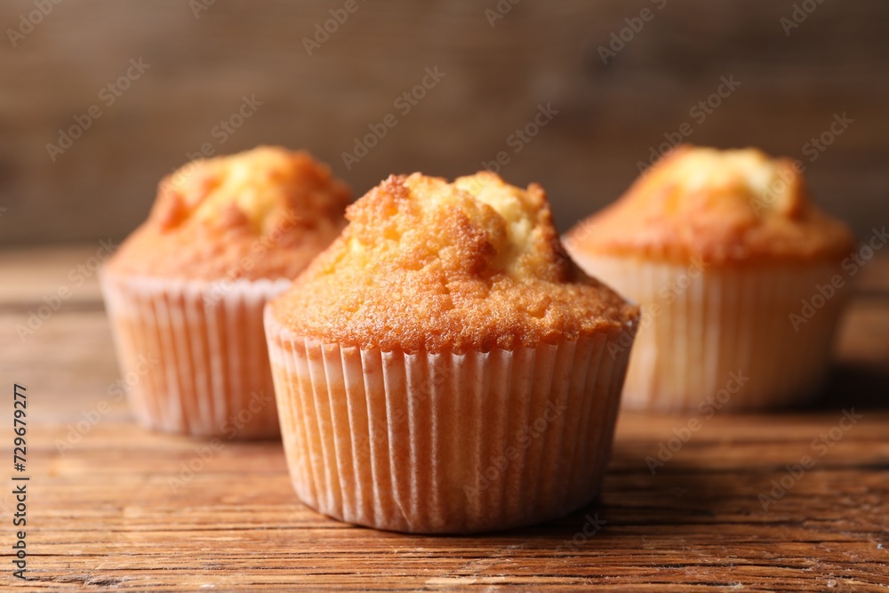 Delicious sweet muffins on wooden table, closeup Delicious sweet muffins on wooden table, closeup