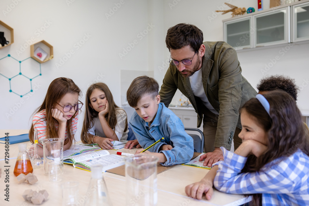 Man teacher with kids during chemistry lesson in school classroom. Man teacher with kids during chemistry lesson in school classroom.