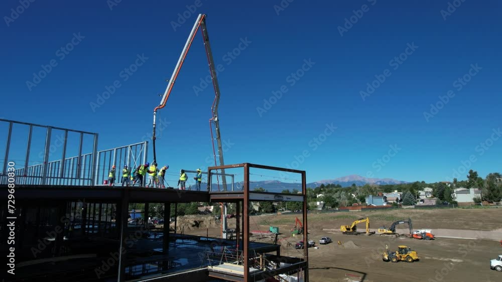 Aerial view of construction workers pouring concrete on a commercial building near the mountains Aerial view of construction workers pouring concrete on a commercial building near the mountains