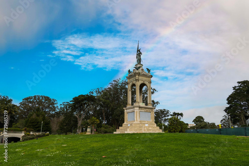 A statue of a woman in the center of the courtyard at Golden Gate Park with green trees, plants and grass in San Francisco California USA photo