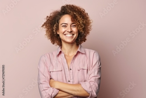 Portrait of a smiling young woman with curly hair over pink background