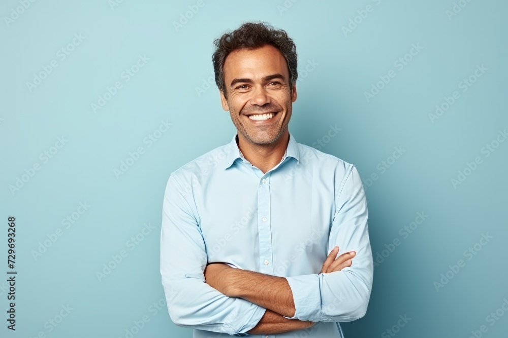 Portrait of a handsome young man smiling with arms crossed against blue background Portrait of a handsome young man smiling with arms crossed against blue background