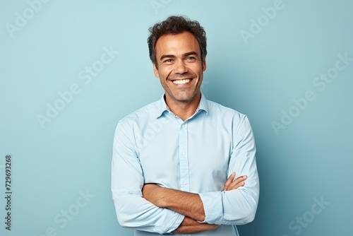 Portrait of a handsome young man smiling with arms crossed against blue background