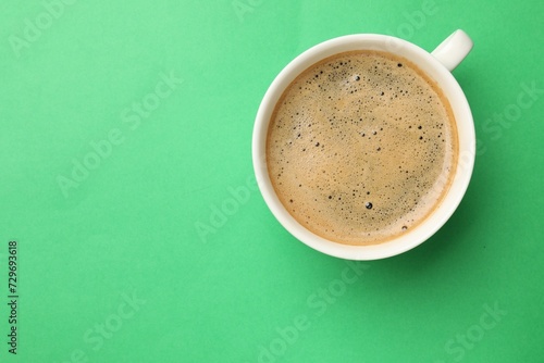 Aromatic coffee in cup on green background, top view. Space for text