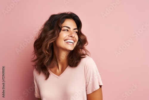 Portrait of happy smiling young woman looking at camera over pink background