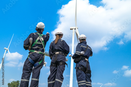 Engineers man and woman inspecting construction of WIND TURBINE FARM. WIND TURBINE with an energy storage system operated by Super Energy Corporation. Workers Meeting to check AROUND THE AREA.