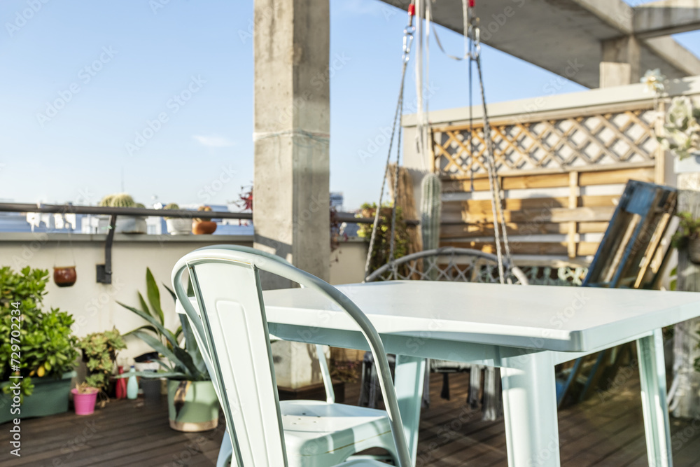 Obraz premium An urban terrace with plants and a metal table with matching chairs