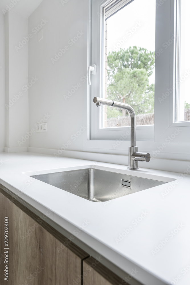 Kitchen faucet with stainless steel bowl embedded in the countertop under an aluminum window Kitchen faucet with stainless steel bowl embedded in the countertop under an aluminum window