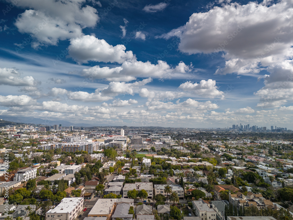 Aerial panorama of residential neighborhood streets of West Hollywood and city of Los Angeles cityscape panorama with fluffy clouds, downtown LA skyline in background