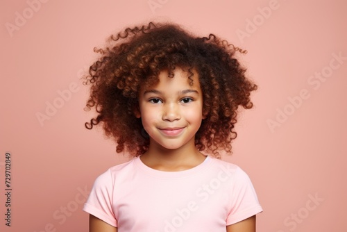 Portrait of a smiling little african american girl with curly hair on a pink background © Iigo