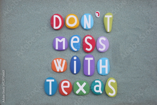 Don't mess with Texas, slogan for a campaign aimed at reducing littering on Texas roadways by the Texas Department of Transportation composed with multi colored stone letters over green sand
