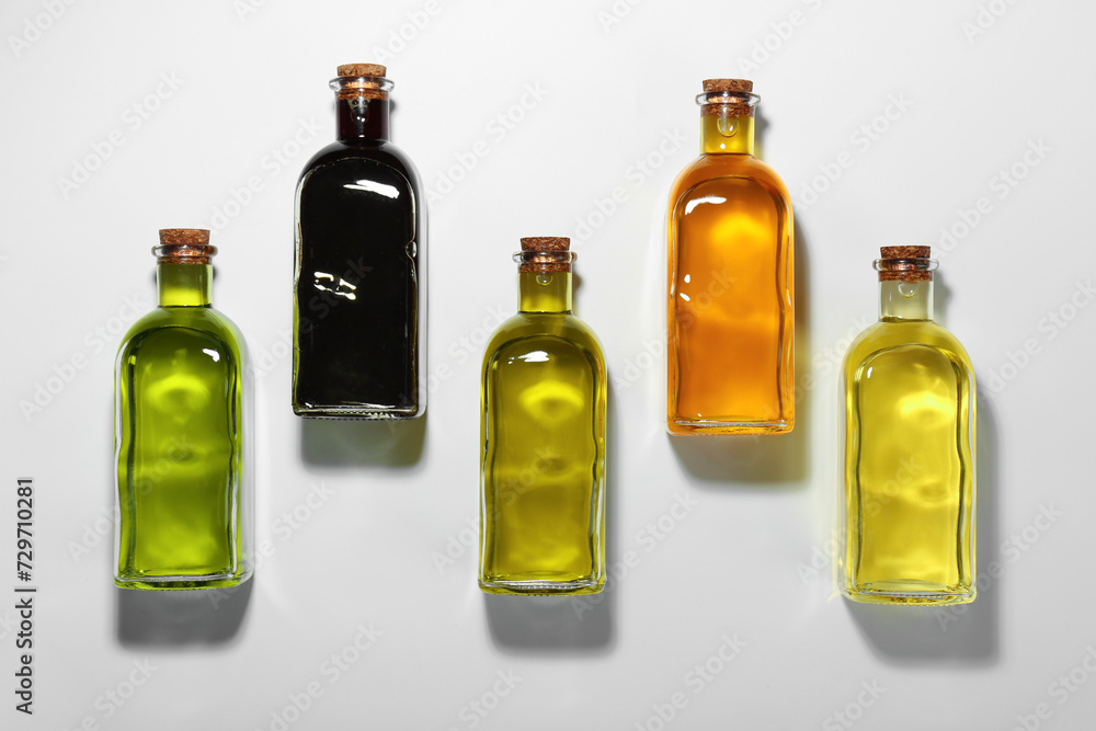 Vegetable fats. Different cooking oils in glass bottles on white background, flat lay Vegetable fats. Different cooking oils in glass bottles on white background, flat lay