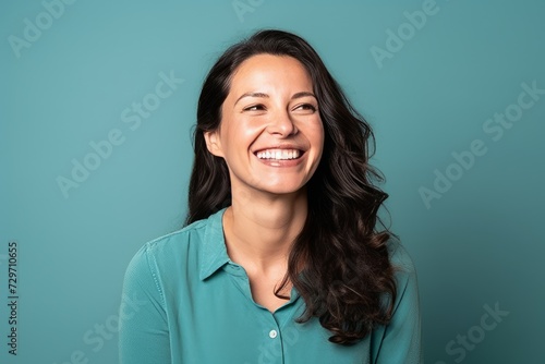 Portrait of a happy young woman laughing and looking up against blue background