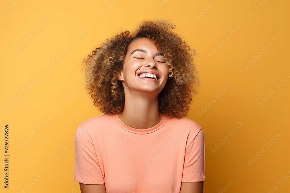 Young african american woman with curly hair laughing on yellow background Young african american woman with curly hair laughing on yellow background