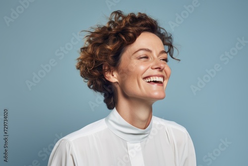 Happy young woman with curly hairstyle and white shirt on blue background